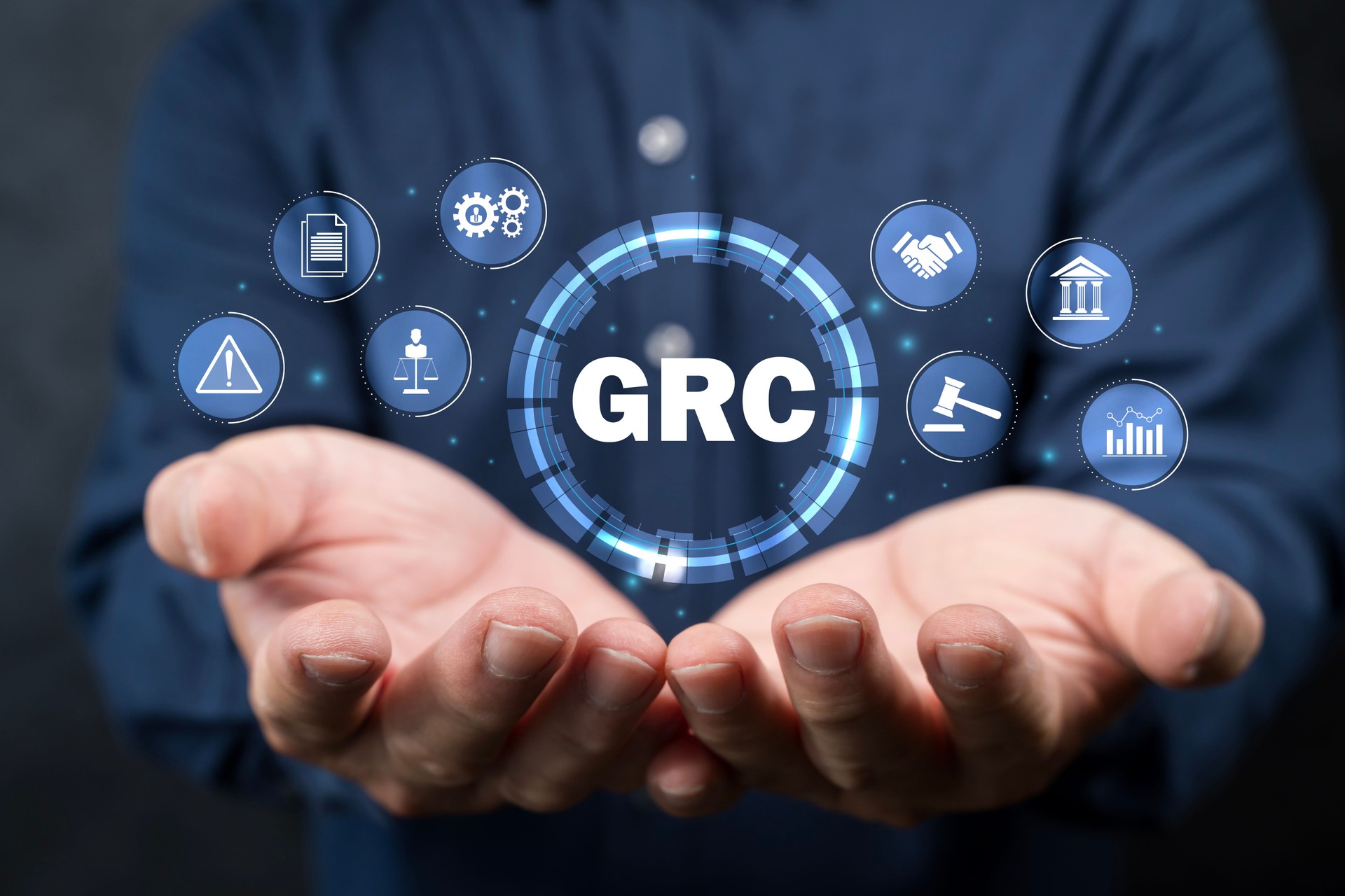 GRC, Governance Risk and Compliance concept. Businessman holding GRC icon on digital screen.
